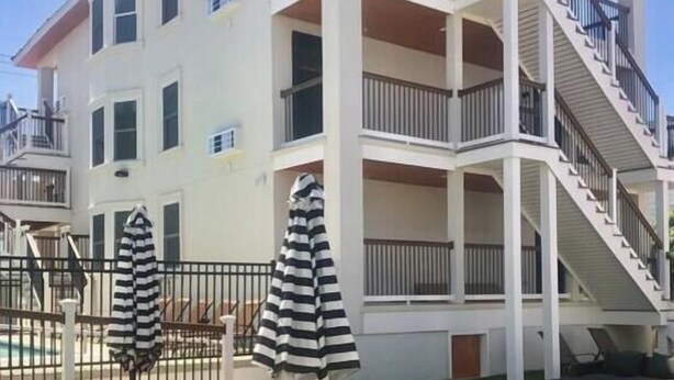 A multi-story building with a pool, outdoor seating, and a staircase leading to the upper floors.