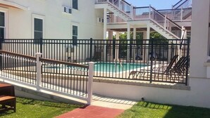 A two-story building with a pool and a fenced patio area.