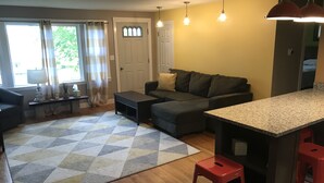 Ein modernes Wohnzimmer mit einer Couch, einem Couchtisch und einer Küchenzeile mit einer Granitabdeckung und roten Barhocker.