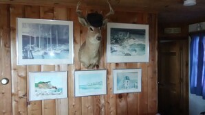 En vägg av trä med inramade bilder av landskap och ett rådjurshuvud.