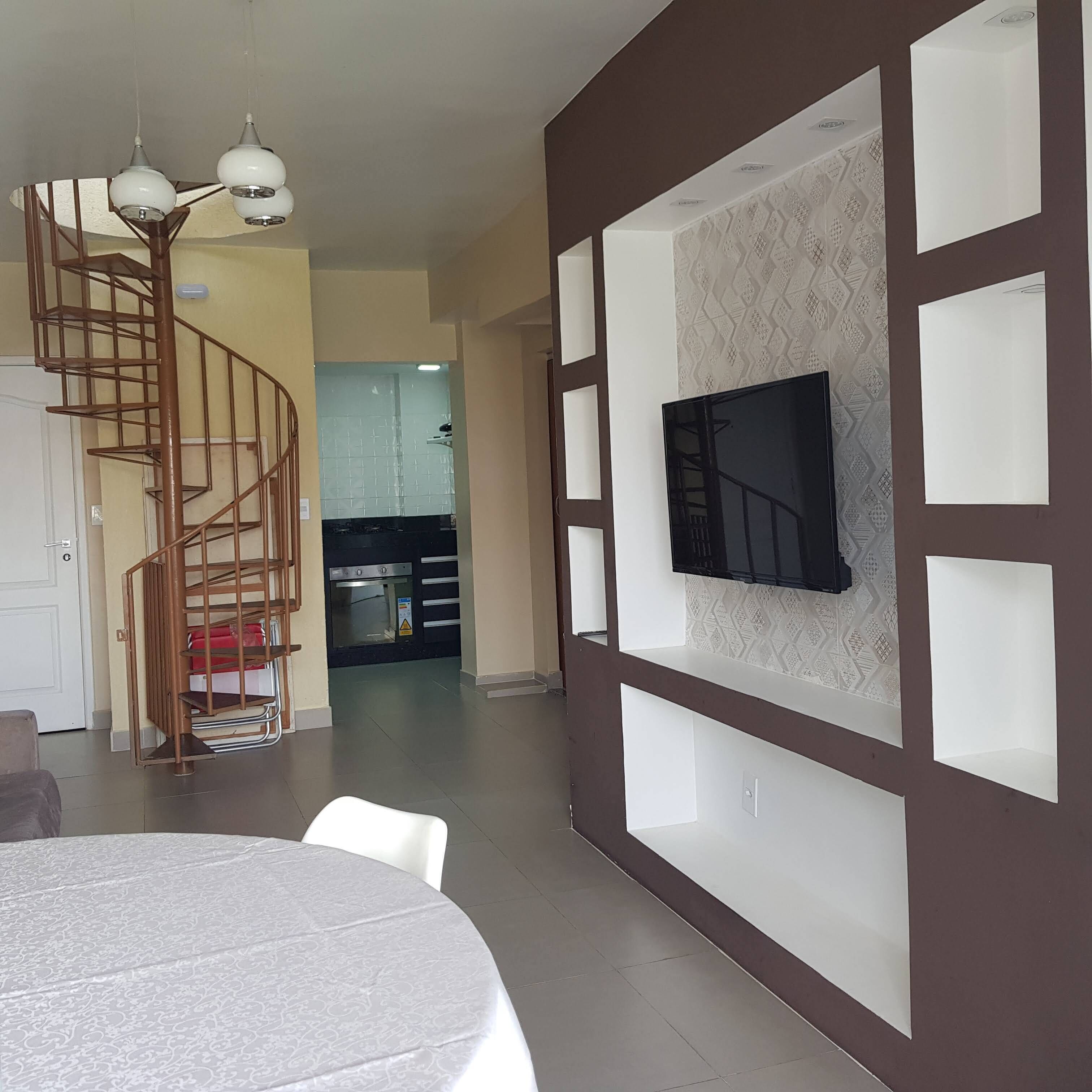 Ein modernes Wohnzimmer mit Wendeltreppe, einem Essbereich und einer Küche im Hintergrund.