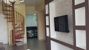 Ein modernes Wohnzimmer mit Wendeltreppe, einem Essbereich und einer Küche im Hintergrund.