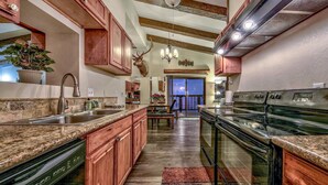 A kitchen with granite countertops, wooden cabinets, a dishwasher, a stove, and a chandelier. - Mv50 Grand Lodge Lake Tahoe With Game Room Hot (Stateline)