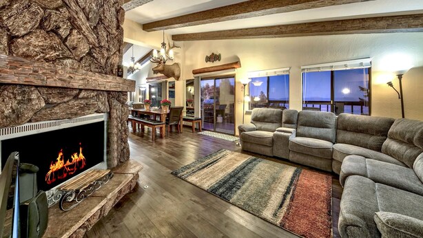 A cozy living room with a stone fireplace, comfortable seating, and a dining area. - Mv50 Grand Lodge Lake Tahoe With Game Room Hot (Stateline)