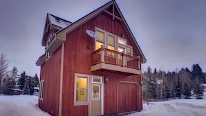 A two-story wooden house with a balcony, a garage, and a satellite dish.