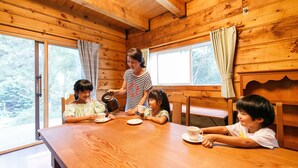 A wooden cabin interior with a dining table, chairs, and large windows. - Loghouse Seseragi (Tsuru)