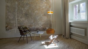 A room with a rustic wall, a round table, a patterned chair, a hanging light fixture, and a radiator. - SPOTinROME designer apartment and luxury, rome historic district III column (Roma)