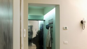 A narrow hallway with a glass door leading to a room. There are coat hooks on the wall and a light switch. - SPOTinROME designer apartment and luxury, rome historic district III column (Roma)