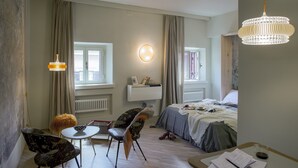 A hotel room with a bed, a desk, a chair, a small table, and a hanging light fixture. - SPOTinROME designer apartment and luxury, rome historic district III column (Roma)