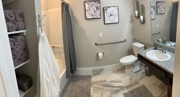 A bathroom with a toilet, sink, and shower. There are towels on shelves and a shower curtain.