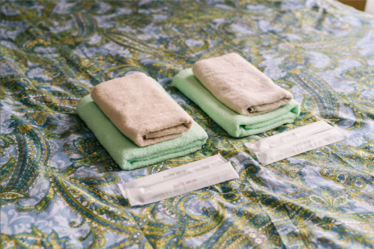 A bed with a patterned bedspread and two folded towels on it.