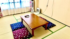 Een kamer met tatami vloerbedekking, een houten tafel en kussens.