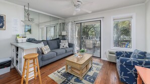 A modern living room with a grey sofa, wooden coffee table, and a blue patterned sofa. - Coral Paradise, Ocean View, Couple's Seaside Retreat, Pool, Walk to Shops Dining (Hilton Head Island)