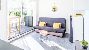 Un salon moderne avec un canapé gris, des coussins jaunes, une petite table basse en bois et une plante en pot.
