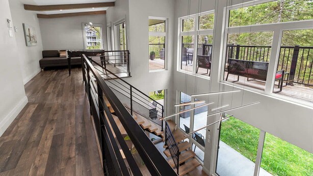 Un interior espacioso con techo alto, una escalera y ventanas amplias que ofrecen vistas al exterior.