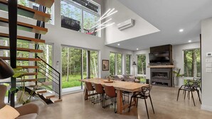 Un salón amplio con mesa de comedor, sillas, chimenea y un televisor grande.