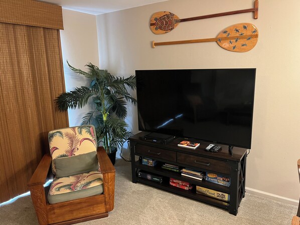 A living room with a flat-screen TV, wooden entertainment unit, and a decorative paddle. - Luxurious One Bedroom, Two Bath Condo in South Kihei; Sleeps 4 (Kihei)