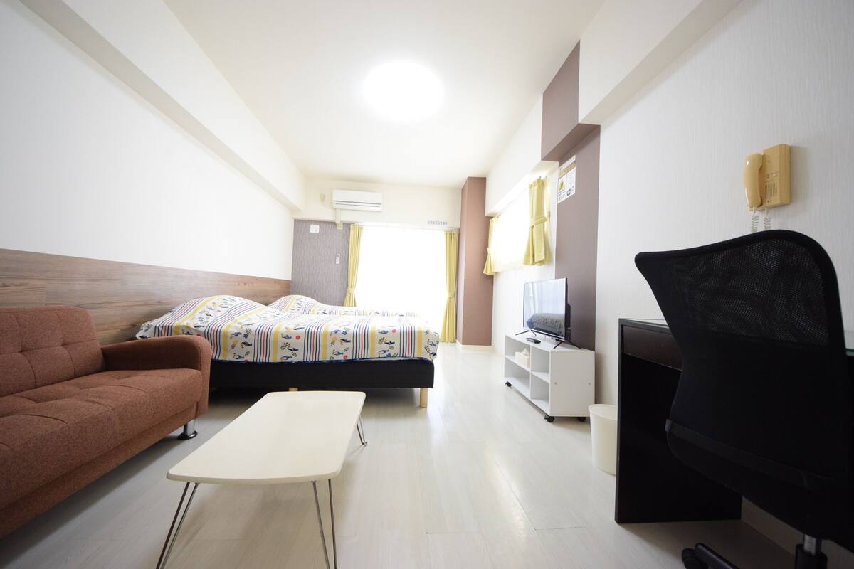 Een hotelkamer met een bed, een bank, een televisie, een bureau en een stoel.