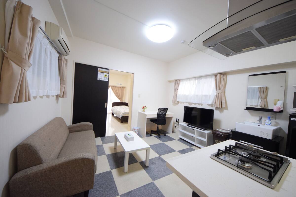 Een compacte hotelkamer met kitchenette, een bank, een eettafeltje en een bed.