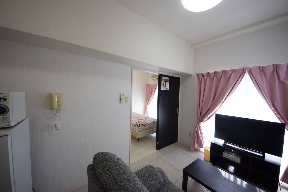 Een hotelkamer met een bed, televisie, bureau en telefoon.