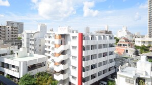 A multi-story residential building with balconies and a red vertical element. - SUMUKA Asato Station (Naha)