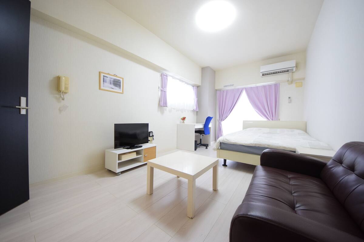 Een hotelkamer met een bed, een televisie, een bureau, een stoel en een bank.