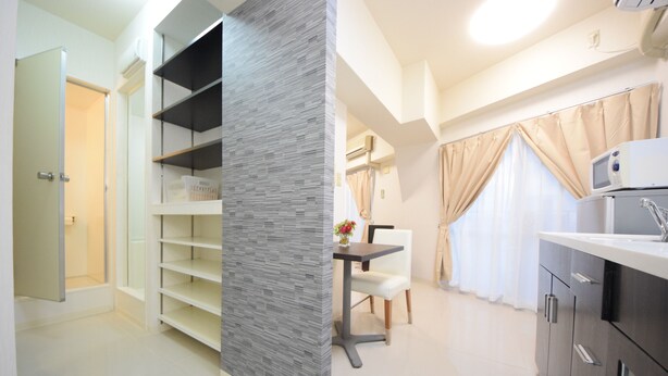 A modern kitchen with grey cabinets, a white countertop, and a dining area with a table and chairs. - SUMUKA Asato Station (Naha)