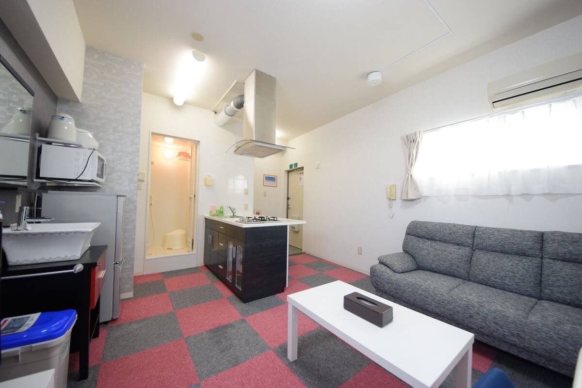 Een knus woongedeelte met een kitchenette, een bank en een eettafel.