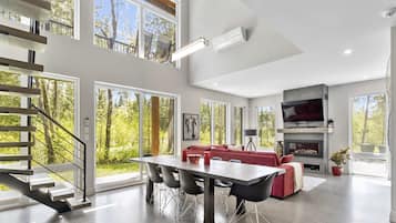 Un intérieur spacieux comprenant un coin repas, un canapé rouge, une cheminée et un escalier menant à un balcon.