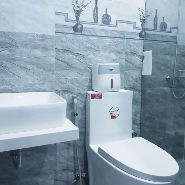 A modern bathroom with a white sink, toilet, and shower. - Sena Home (Da Nang)