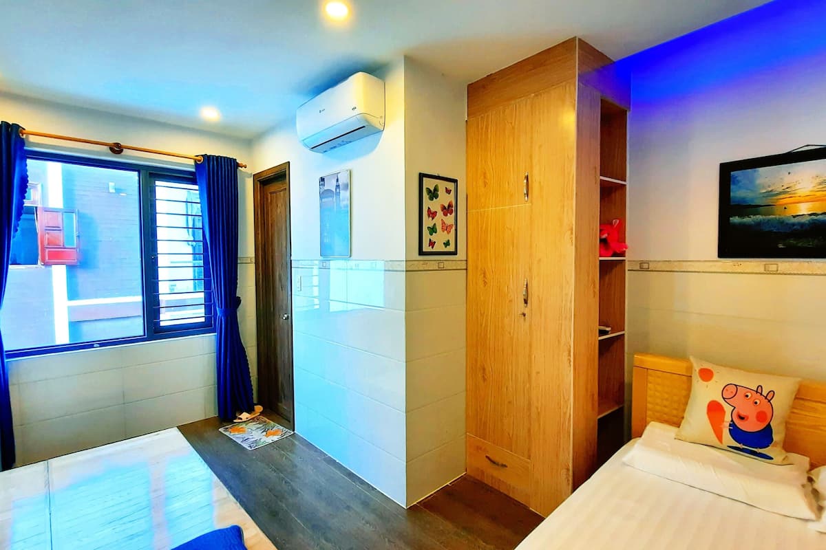 A bedroom with a bed, a wardrobe, a TV, and a window with curtains.