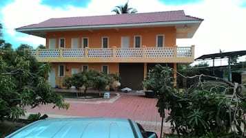 A two-story building with a red-tiled roof and a balcony with a lattice railing.