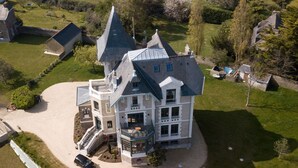 Et stort, flereetages hus med et markant tårn og en rummelig indkørsel.
