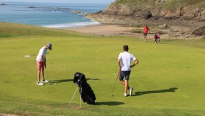 En golfbane med udsigt til havet og klipper.