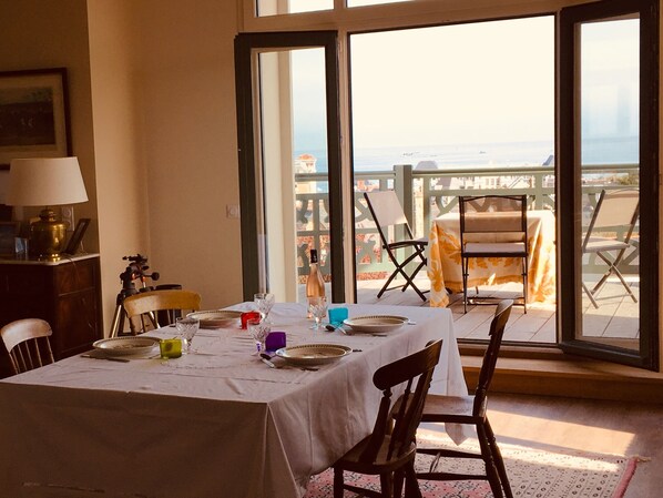 Een eethoek met een tafel gedekt voor vier personen, een statief en een lamp op een bureau.