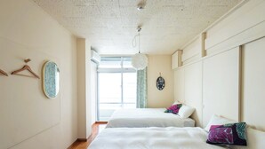 A hotel room with two beds, a large window, and a ceiling with a speckled pattern. - Pineapple Hotel (Naha)
