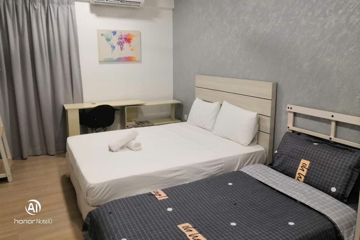 Une chambre d’hôtel avec un lit, un bureau et une chaise. Il y a un climatiseur au mur et un tableau accroché au mur.