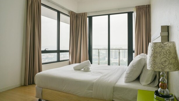 A hotel room with a large bed, beige curtains, a view of the city, and a green nightstand with a lamp. - USJ One Premium Suites at Subang Sunway USJ (Subang Jaya)