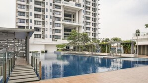A modern building with a swimming pool, outdoor seating, and a covered area with greenery. - USJ One Premium Suites at Subang Sunway USJ (Subang Jaya)