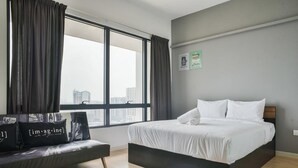 A modern hotel room with a large window, a bed, a sofa, and a blue mat on the floor. - USJ One Premium Suites at Subang Sunway USJ (Subang Jaya)