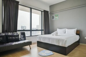 Una habitación de hotel moderna con un ventanal grande, una cama, un sofá y un tapete azul en el suelo.