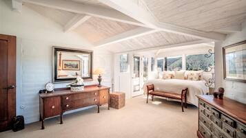 A bedroom with a large bed, wooden furniture, and a view of the outdoors.