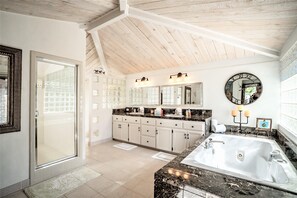 Un baño espacioso con una bañera grande, una ducha a pie y un lavamanos con espejo.