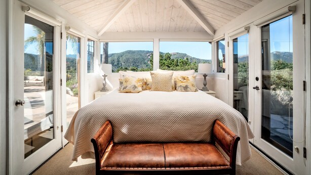 A bedroom with a large bed, a bench, and a view of the mountains. - Lx16: Valley View Estate Above The Wineries With Hot Tub (Carmel Valley)