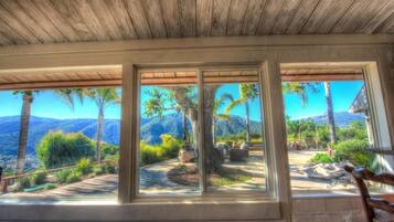 A room with large windows overlooking a landscaped garden and mountains.