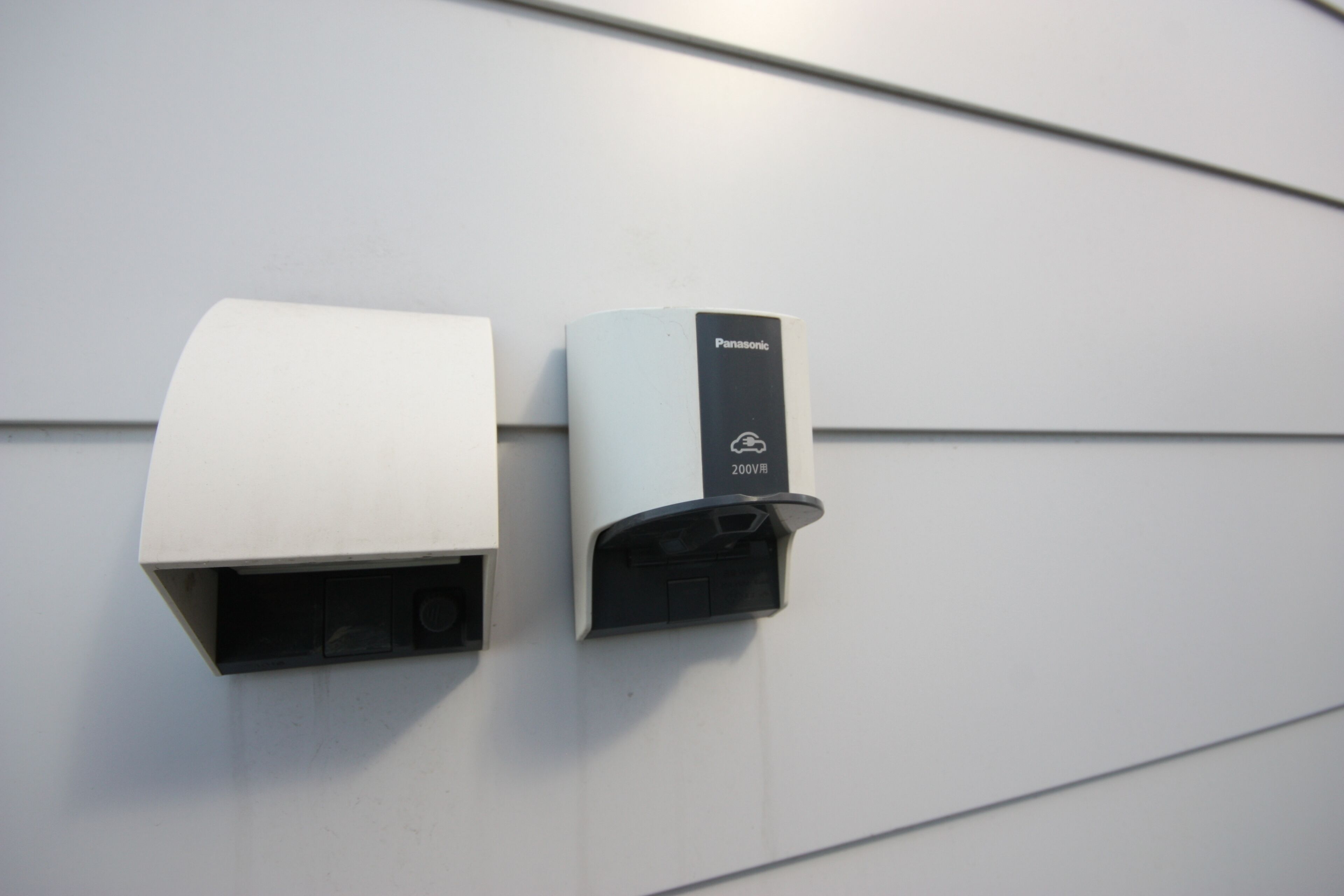 Deux appareils fixés au mur, l’un doté d’un boîtier blanc et l’autre d’un boîtier noir, et portant tous deux les mentions « Panasonic » et « 200 V ».