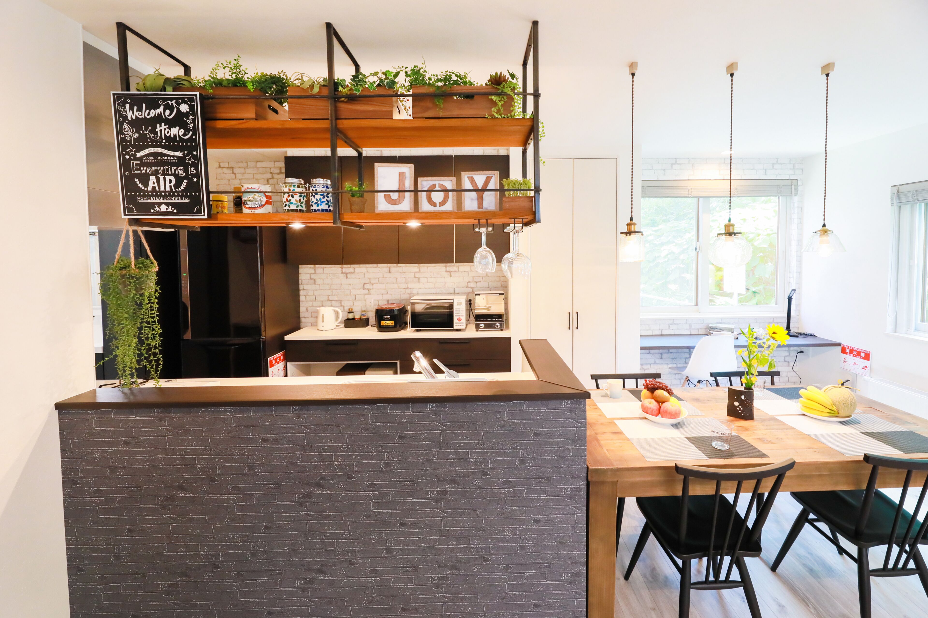 Una cocina moderna con un detalle de pared de ladrillo, estantes de madera con plantas y un letrero de pizarra.