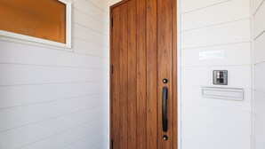 Eine Holztür mit Griff, ein Fenster mit mattiertem Glas und ein Namensschild an der Wand.