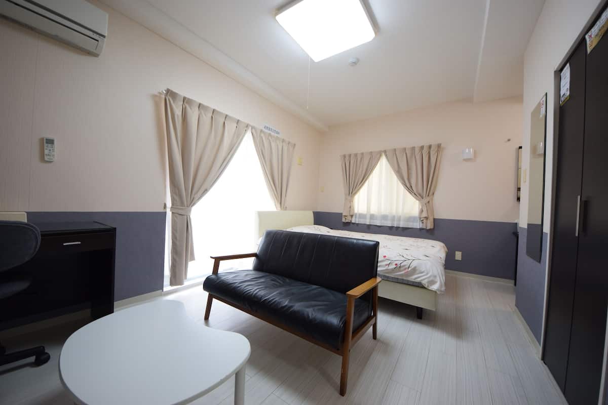 A hotel room with a bed, a sofa, a desk, and a small table.