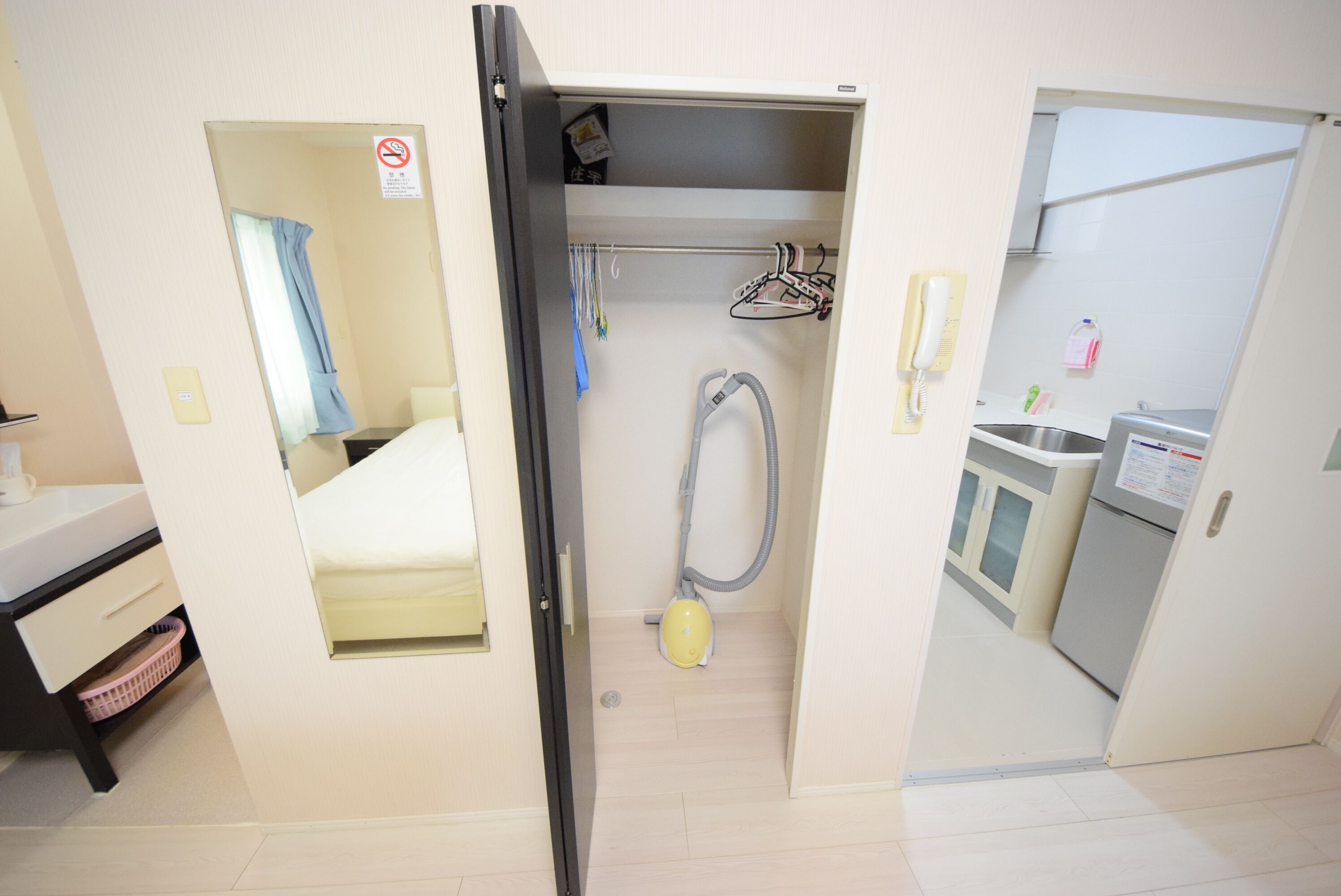 A hotel room with a bed, a bathroom with a shower, a sink, and a small kitchen area.